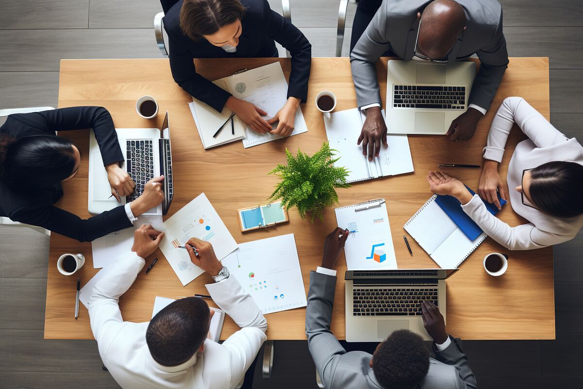 A team reviewing charts and laptops around a conference table, seen from above
